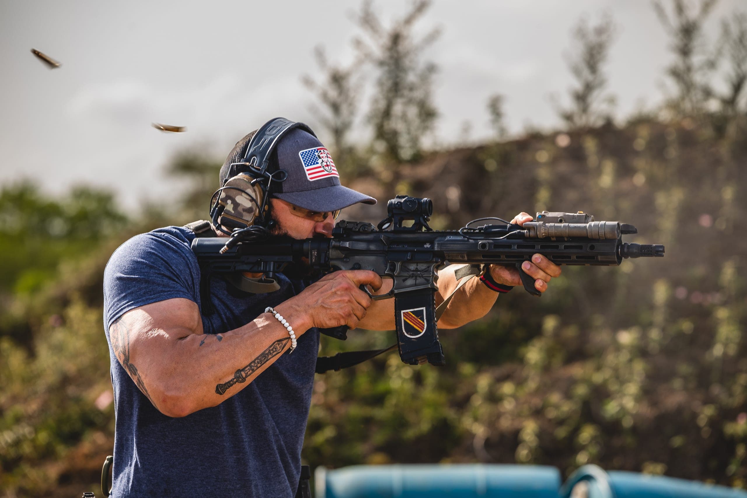 A shooter firing a carbine with spent brass in the air
