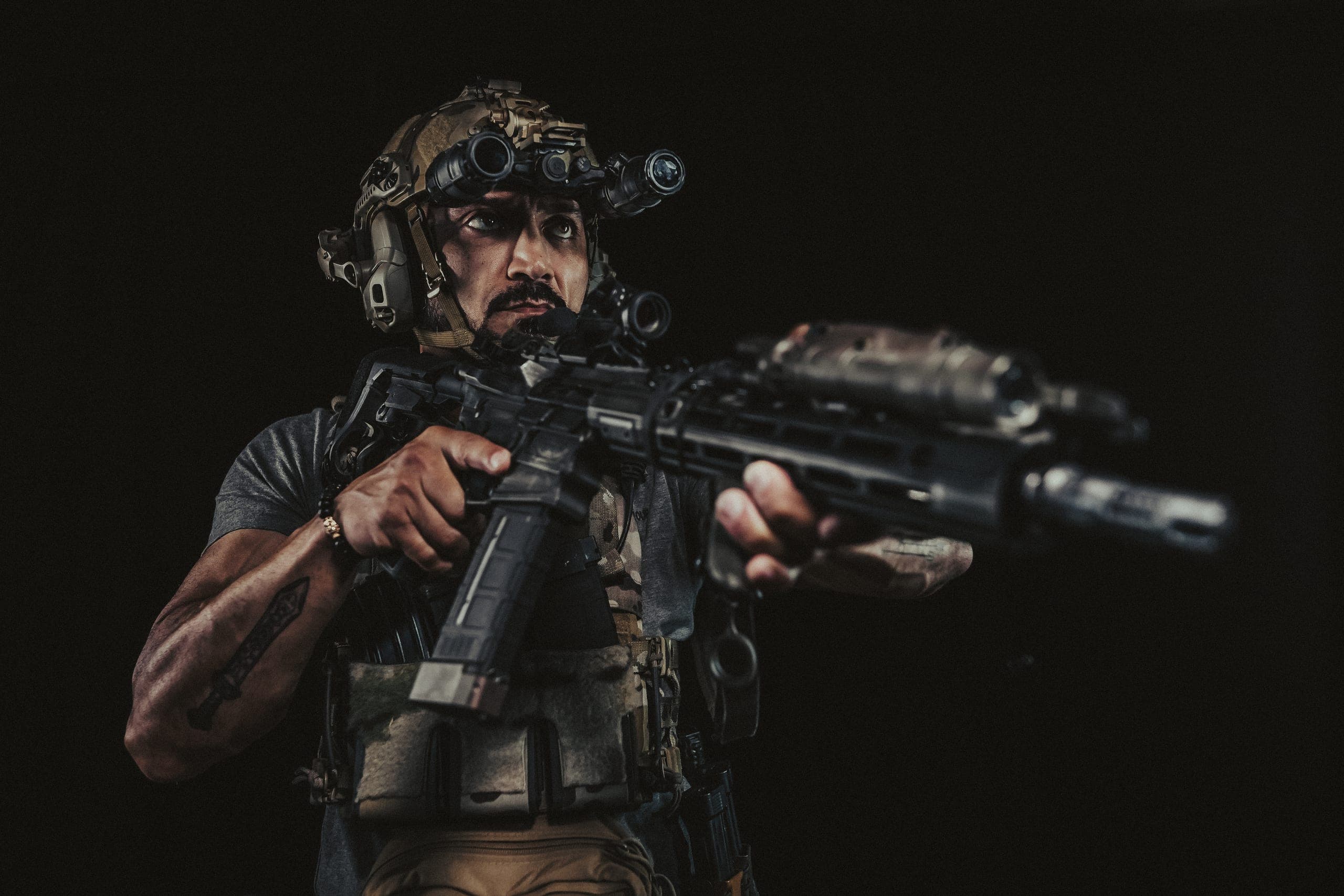 An operator under night vision lit by coloured practical light in a warehouse